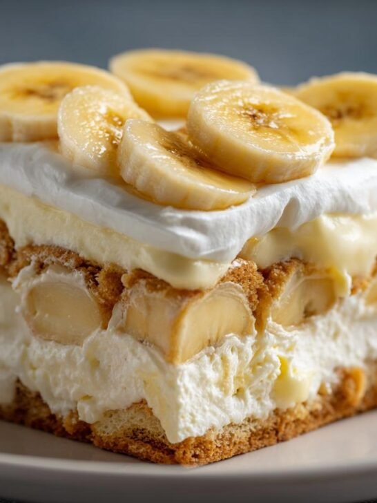 A slice of creamy banana pudding recipe layered with vanilla wafers and fresh banana slices, topped with whipped cream.