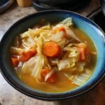 A close-up of a bowl filled with a delicious cabbage soup recipe, featuring tender cabbage and carrots in a savory broth.