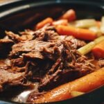 Close-up of shredded beef with carrots and celery in a crock pot, showcasing one of the best crock pot recipes.