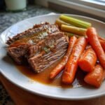 Close-up of tender sliced pot roast with rich gravy, served with carrots and celery, a perfect example of crockpot recipes.