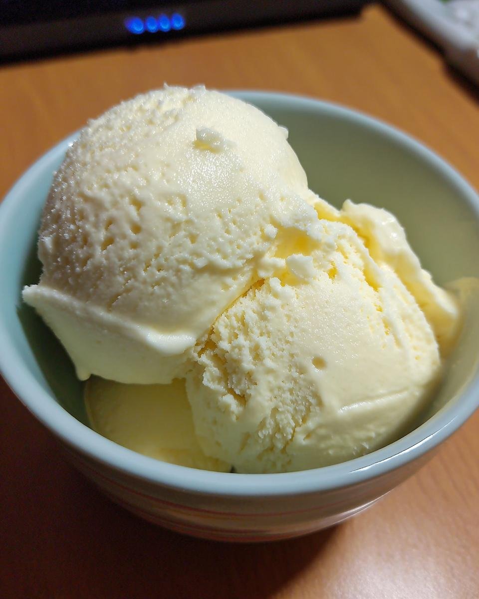 A close-up of a light yellow, creamy Delightful Frozen Yogurt in a light blue bowl.