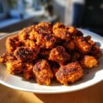 A pile of golden-brown, crispy Flavorful Cajun Chicken Bites on a white plate, ready to be enjoyed.