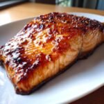 A close-up of an irresistible honey glazed salmon fillet, glistening with a rich, amber glaze, ready for dinner.