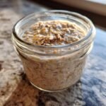 Close-up of a glass jar filled with creamy overnight oats recipe, showing oats, chia seeds, and a hint of cinnamon.