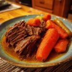 A close-up of a plate of tender pot roast with carrots, a classic dish from crock pot recipes.