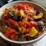 Close-up of a rustic bowl filled with a vibrant ratatouille recipe, featuring tender chunks of eggplant, zucchini, tomatoes, and bell peppers.