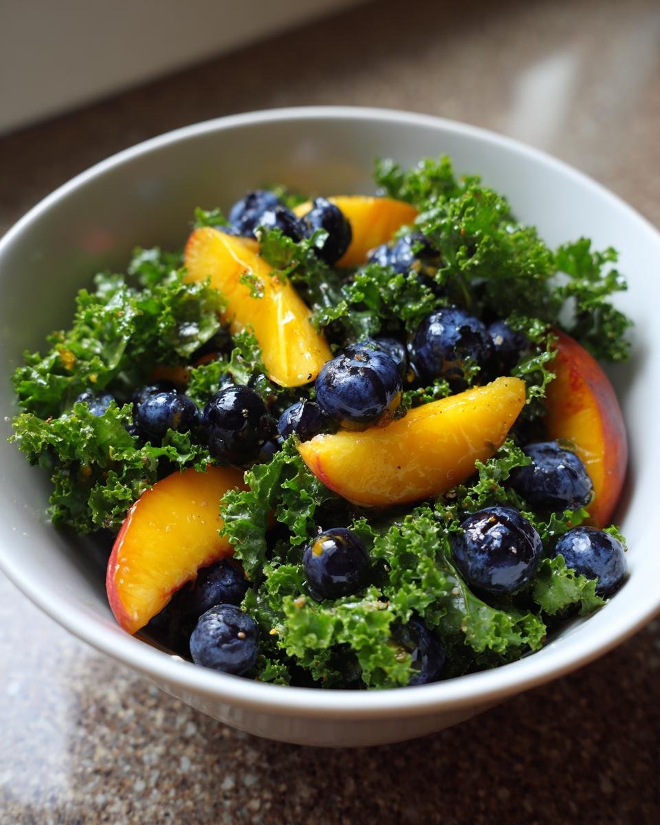 Close-up of a Refreshing Summer Peach and Blueberry Kale Salad in a white bowl, showcasing vibrant kale, sliced peaches, and blueberries.