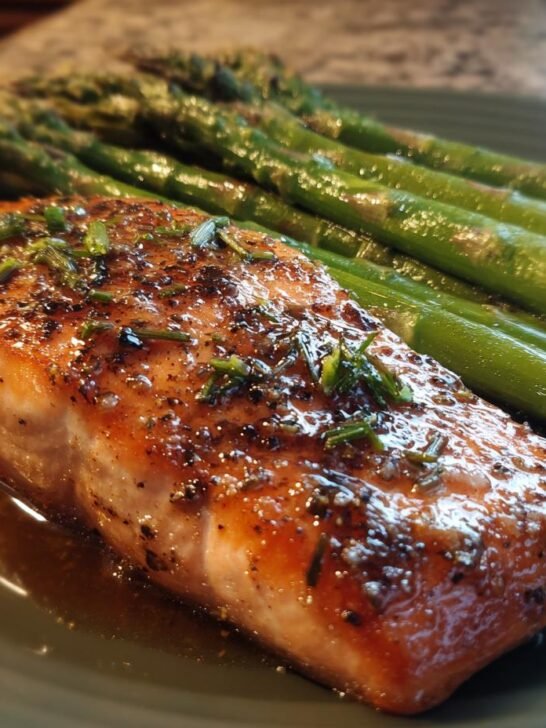 A perfectly cooked salmon fillet with herbs and spices, served alongside roasted asparagus spears, ideal for easy dinner recipes.