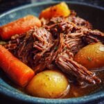 Close-up of a bowl filled with shredded pot roast, tender carrots, and whole potatoes, showcasing one of the best slow cooker recipes.