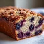 Close-up of a loaf of Almond Cinnamon Crunch Blueberry Banana Bread showing moist crumb and blueberries.