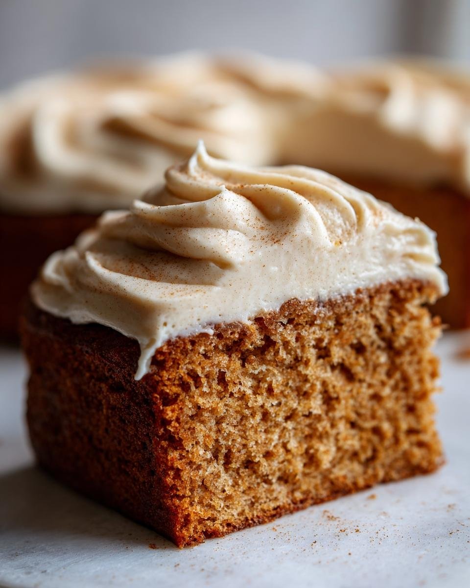 A slice of moist Apple Cider Cake topped with swirls of Cinnamon Maple Buttercream, dusted with cinnamon.