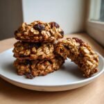 A stack of three Apple Oatmeal Raisin Breakfast Cookies with one cookie broken open to show the soft interior.