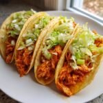 Four crispy tacos filled with shredded orange buffalo chicken and topped with shredded lettuce and celery.