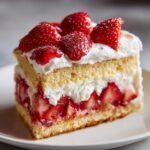 A delicious slice of Best Birthday Strawberry Shortcake with layers of sponge cake, whipped cream, and fresh strawberries.
