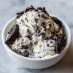 Close-up of scoops of Best No Churn Cookies And Cream Ice Cream topped with cookie crumbles and pieces.