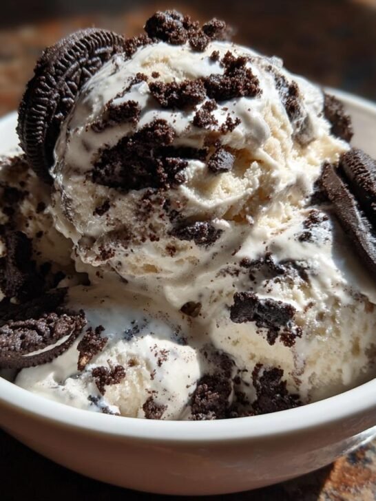 Close-up of creamy scoops of Best No Churn Cookies And Cream Ice Cream topped with cookie pieces and whole cookies.