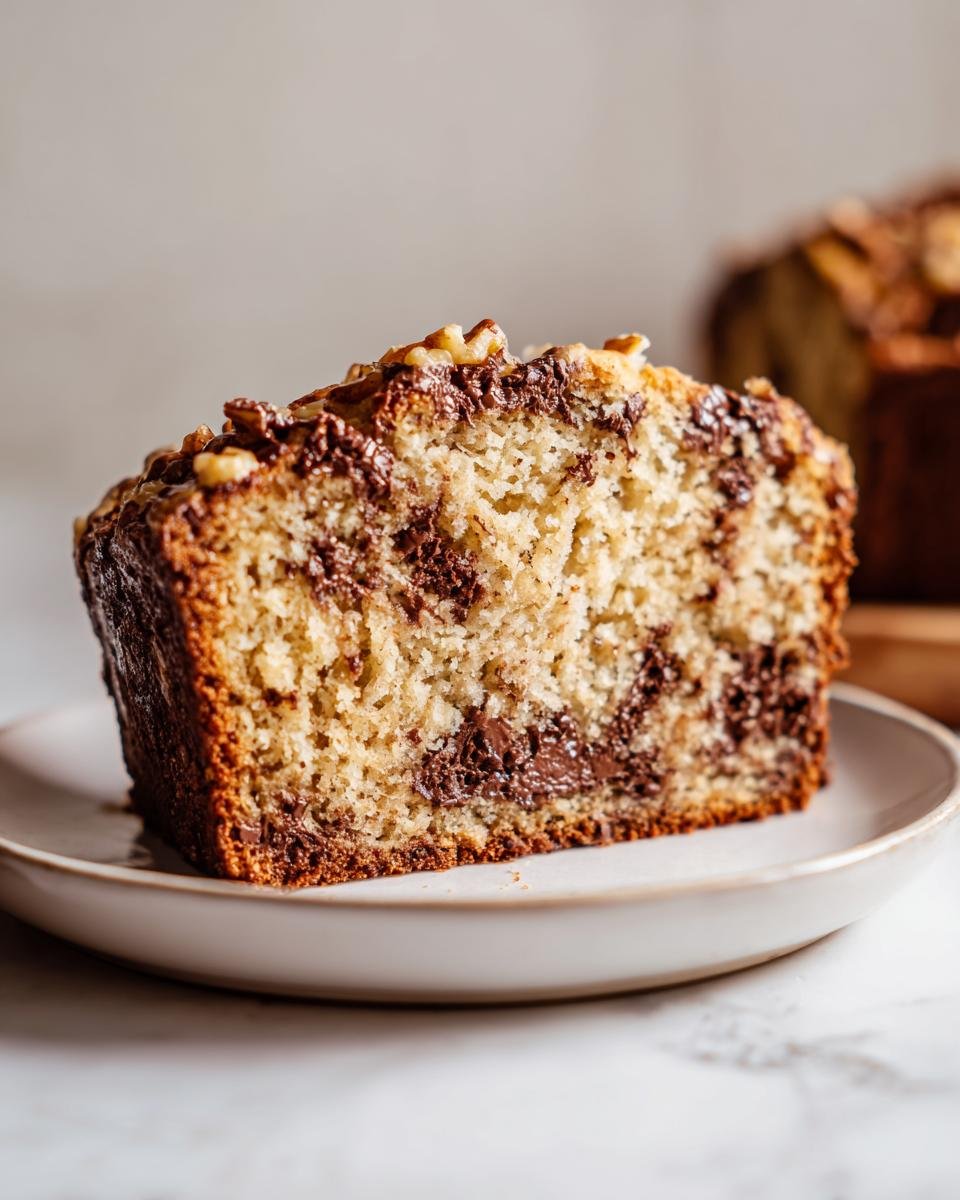 Close-up of a moist slice of Brown Butter Walnut Chocolate Chip Bread showing chocolate swirls and walnuts.