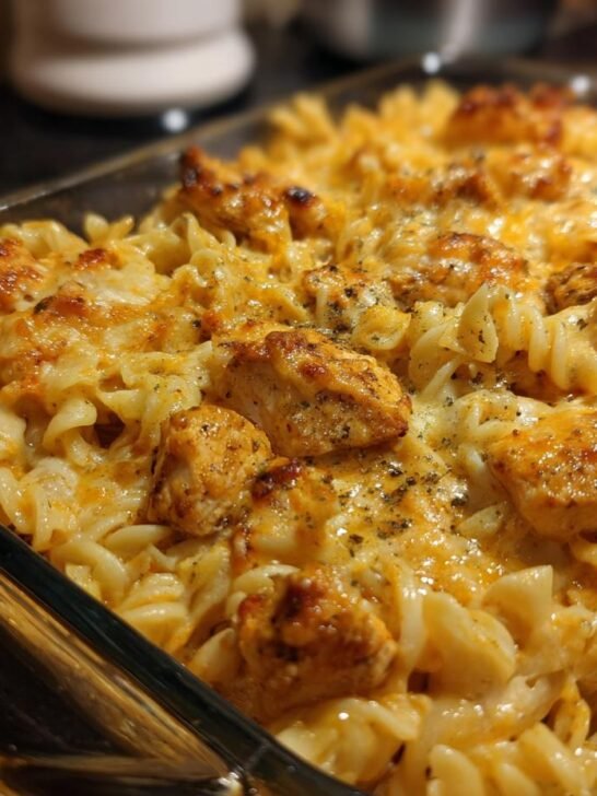 Close-up of Irresistible Cajun Cream Cheese Chicken Pasta Bake, featuring rotini pasta, seasoned chicken pieces, and melted cheese.