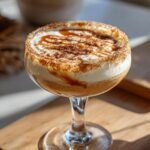 A delicious Caramel Apple Pie Martini topped with whipped cream, caramel drizzle, and cinnamon sugar.