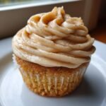 A single Caramel Eggnog Cupcake with thick, swirled caramel frosting dusted lightly with cinnamon.