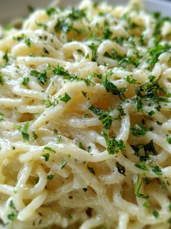 Close-up of pasta coated in Irresistible Creamy Garlic Sauce Recipe, garnished with fresh parsley.