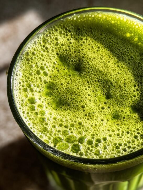 Close-up overhead view of a glass filled with bubbly, creamy pistachio milk.