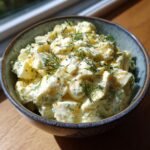A close-up of a bowl filled with Delicious Cottage Cheese Egg Salad, garnished with fresh dill.