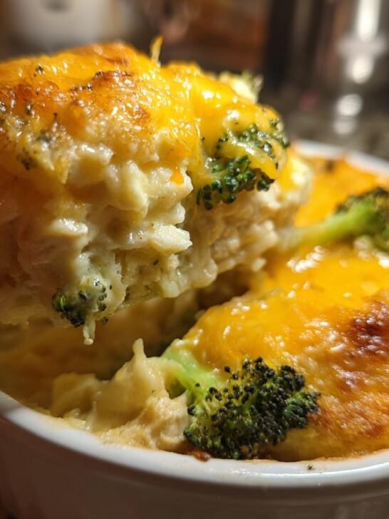 A serving spoon lifts a portion of a Delicious Easy Low Carb Chicken Casserole, showing creamy chicken, broccoli, and melted cheese.