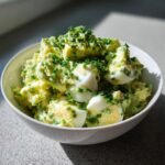 Close-up of a bowl filled with Delicious Keto Avocado Egg Salad, topped with fresh chives.