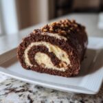 A slice of a Delightful German Chocolate Cake Roll with a creamy filling and chopped nuts on top.