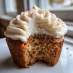 Close-up of an Eggnog Cupcakes Cream Cheese Frosting with a bite taken out, showing the moist crumb.