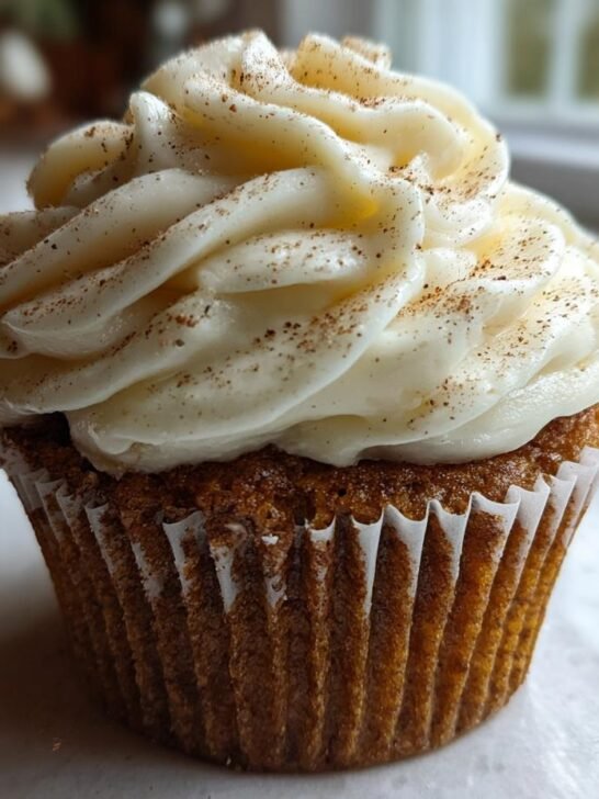 A single, perfectly frosted Eggnog Cupcakes Cream Cheese Frosting, dusted with cinnamon.