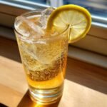 Close-up of a bubbly Fancy Hot Honey Lemon Mocktail served over ice with a fresh lemon wheel garnish.