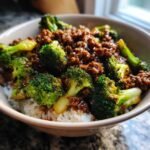 A bowl of white rice topped with flavorful ground beef and broccoli stir fry, showcasing tender beef and vibrant green broccoli florets.
