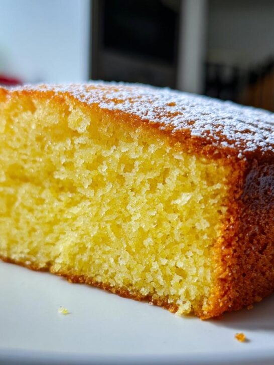 A close-up of a moist slice of Grapefruit Olive Oil Cake, dusted with powdered sugar.