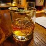 A glass of Hakushu 12 Year Whisky served on the rocks, with a warm amber glow.