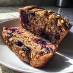 Two thick slices of Healthy Blueberry Oatmeal Breakfast Bread showing moist texture and burst blueberries.