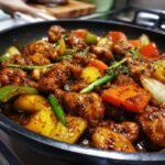 Close-up of Irresistible Chicken Stir Fry With Vegetables in a pan, featuring tender chicken pieces and colorful bell peppers, carrots, and onions in a glossy sauce.