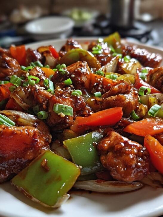 A close-up of Irresistible Chicken Stir Fry With Vegetables, featuring tender chicken pieces and colorful bell peppers, onions, and carrots in a glossy sauce.