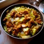 Close-up of Irresistible Chinese Chicken Cabbage Stir Fry in a pan, with tender chicken pieces and crisp cabbage coated in a savory sauce.