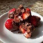 Close-up of irresistible chocolate covered strawberry yogurt clusters, with one cluster broken open to reveal the fresh strawberry inside.