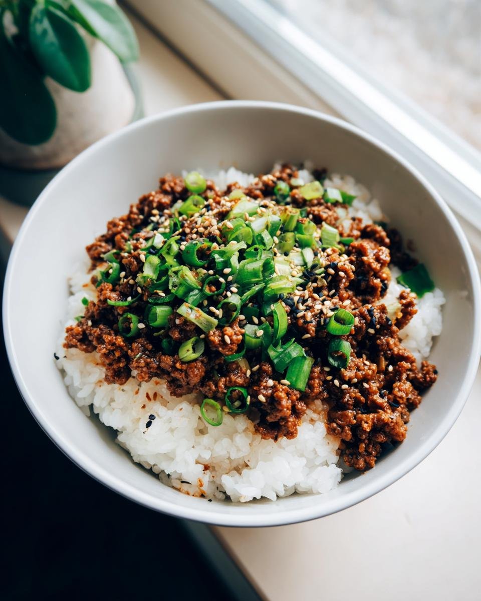 A close-up of an Irresistible Korean Ground Beef Bowl with white rice, seasoned ground beef, and green onions.