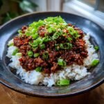 A close-up of an Irresistible Korean Ground Beef Bowl Recipe, featuring seasoned ground beef over white rice, topped with green onions and sesame seeds.