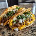 Two Irresistible Smash Burger Tacos filled with seasoned ground beef, melted cheddar cheese, fresh cilantro, and diced onions.