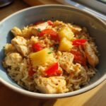 A bowl of Irresistible Tropical Pineapple Chicken Rice Delight, featuring tender chicken, fluffy rice, juicy pineapple chunks, and red bell peppers.