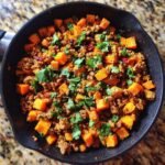 Close-up of an Irresistible Turkey Sweet Potato Skillet, featuring ground turkey and diced sweet potatoes, garnished with fresh cilantro.