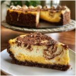 A slice of Mango Cheesecake with a Chocolate Graham Cracker Crust, topped with chocolate shavings.