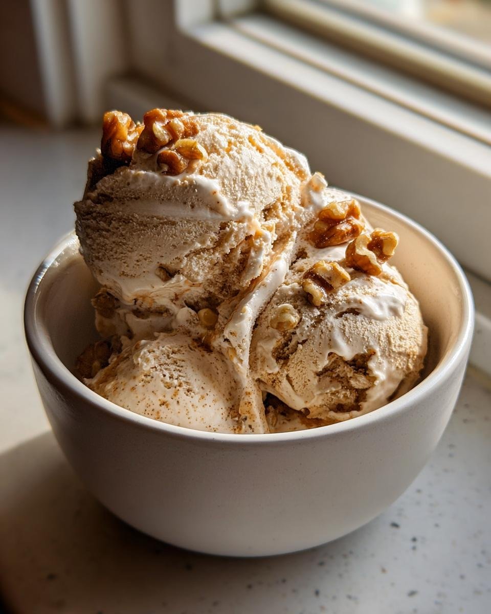 Three scoops of Maple Brown Butter Walnut Ice Cream topped with candied walnuts in a white bowl.