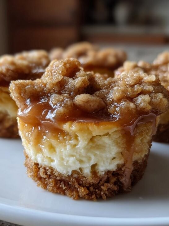 Close-up of Mini Salted Caramel Apple Streusel Cheesecake Bites on a white plate, showing creamy cheesecake and streusel topping.
