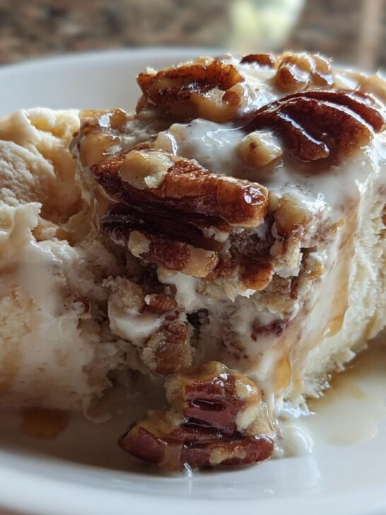 A close-up of a scoop of creamy No Churn Butter Pecan Ice Cream topped with glazed pecans and caramel drizzle.